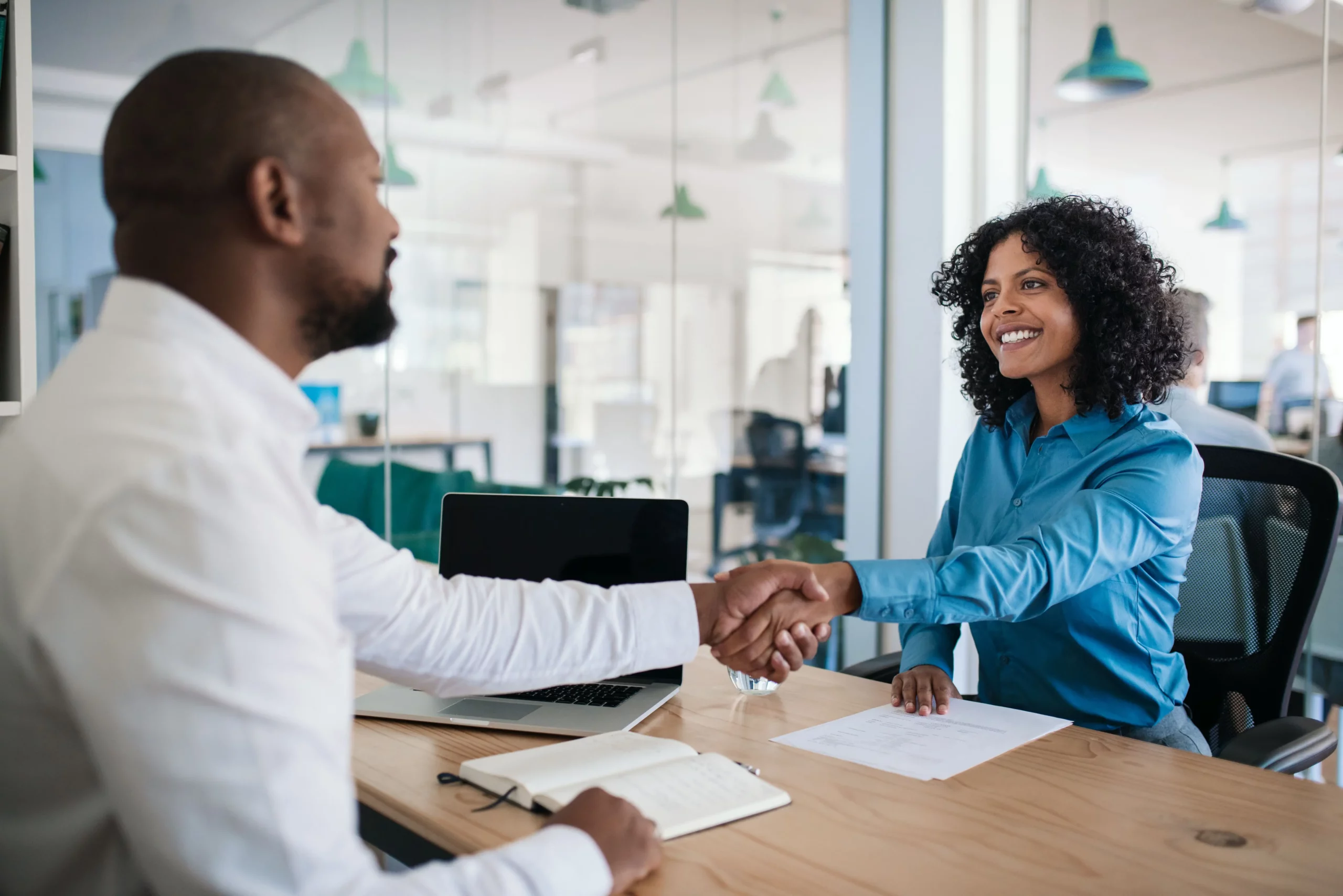 Smiling African American manager sitting at his desk in an office shaking hands